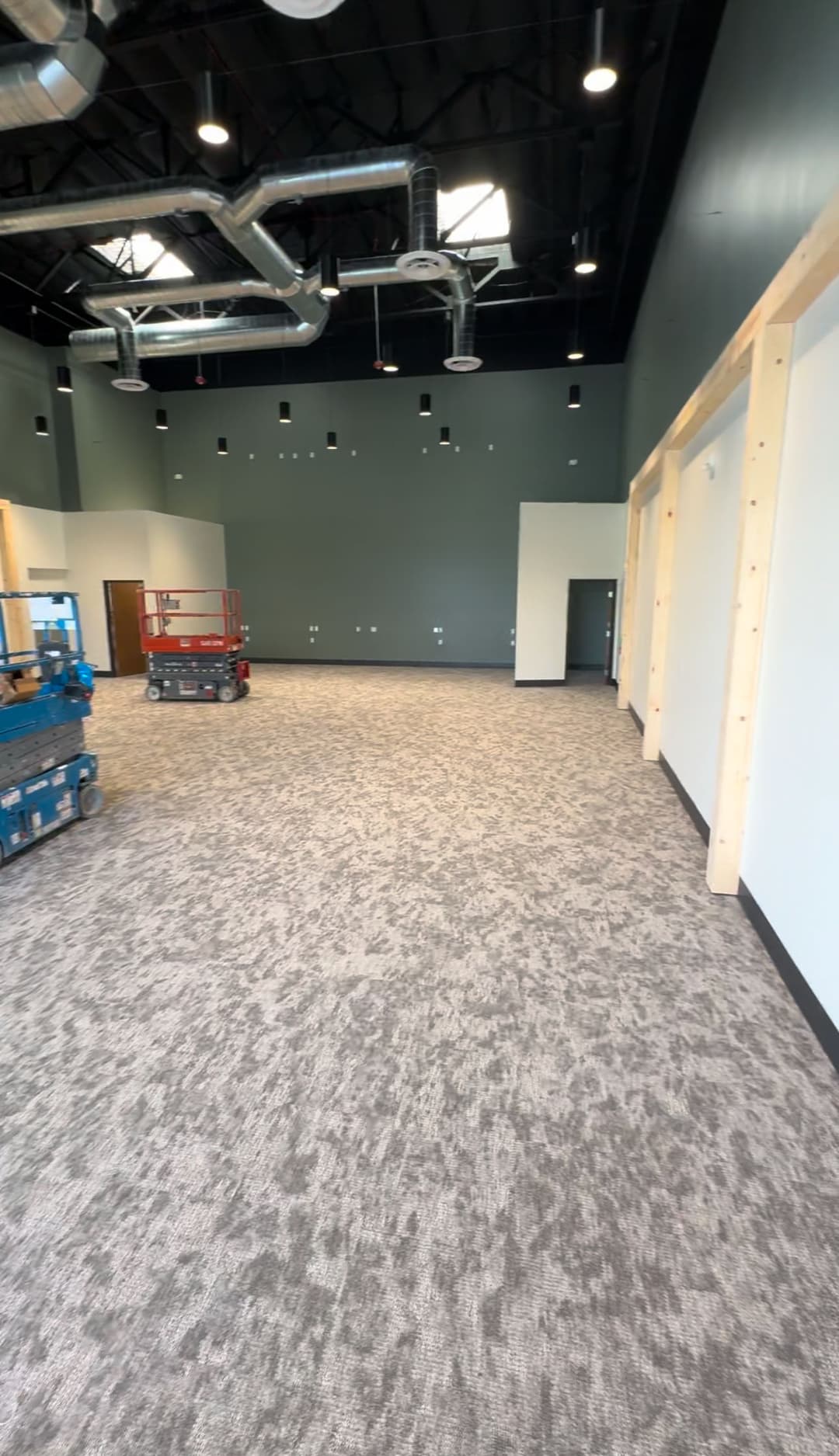Empty commercial space under construction with equipment and freshly laid carpet.