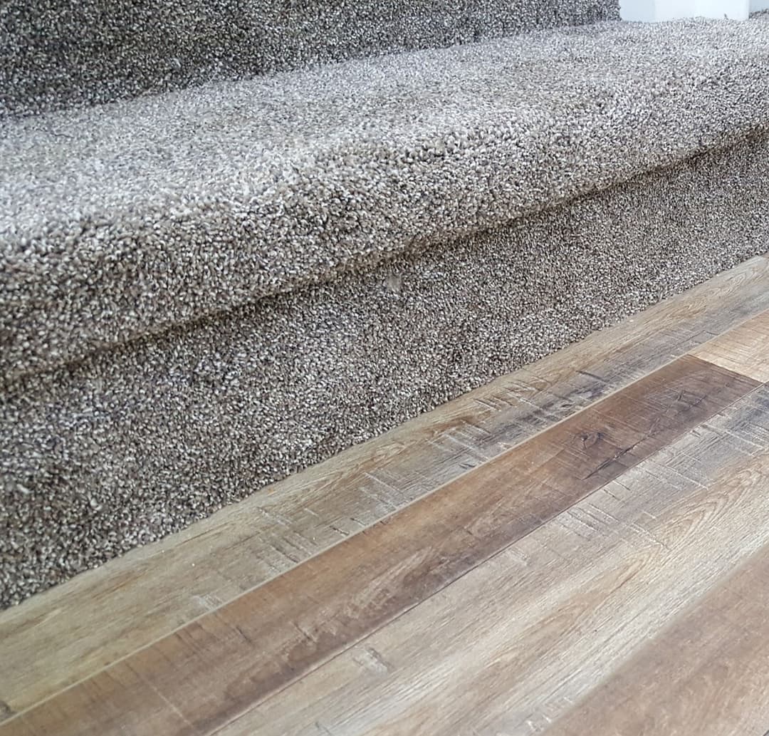 Carpeted stairs with wooden floor, highlighting texture and design contrast.