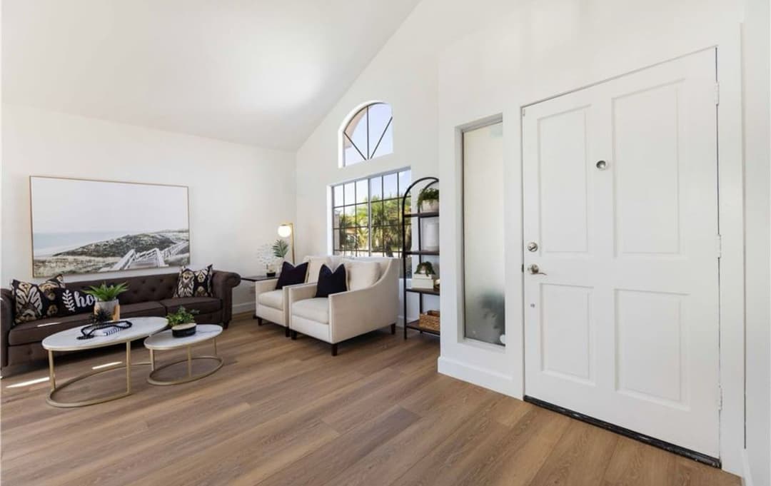 Modern living room with beige couch, stylish decor, and natural light from large windows.
