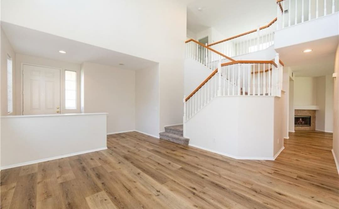 Spacious, well-lit living room with wooden floors and elegant staircase design.