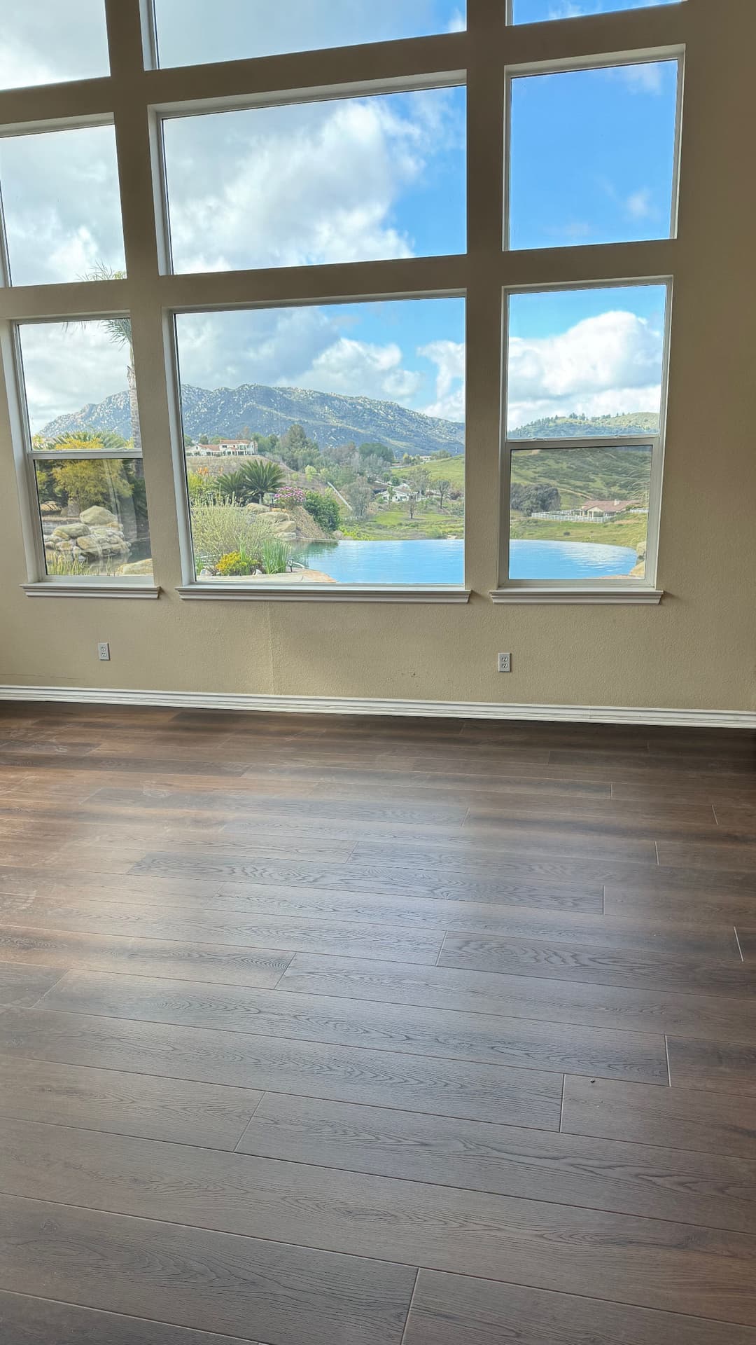 Spacious living room with large windows showcasing a scenic lake and mountains.