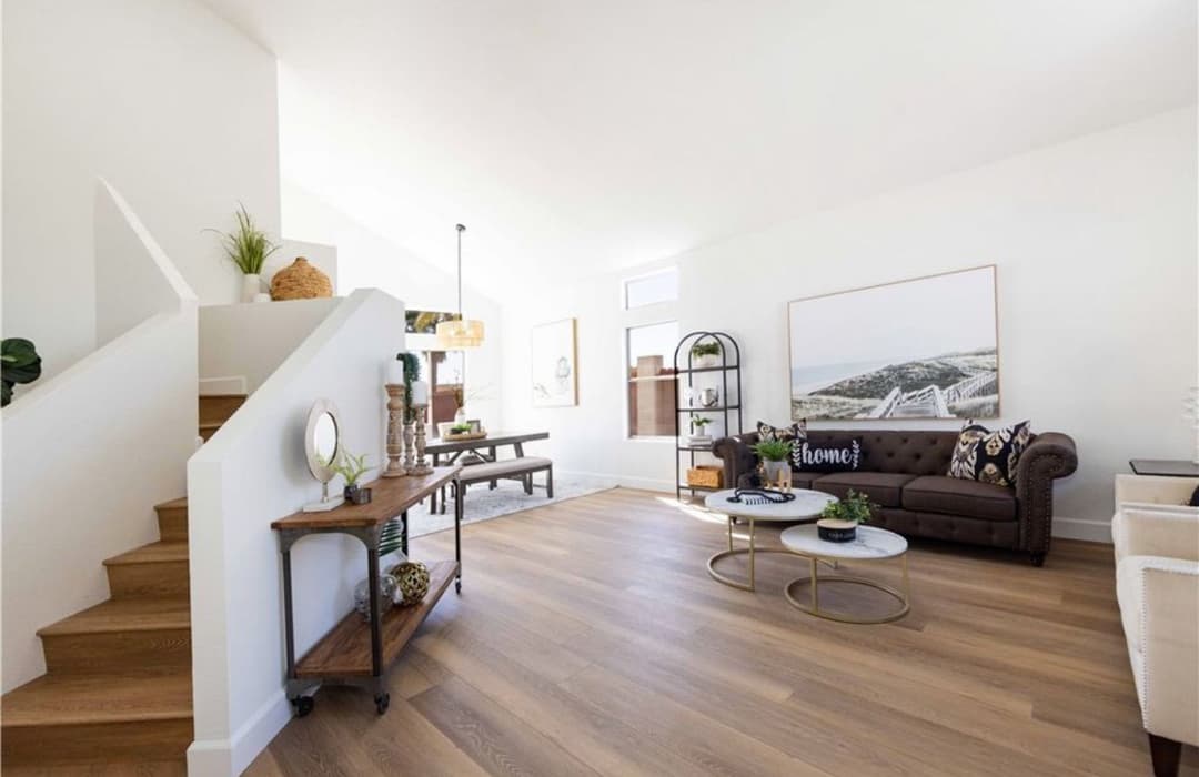Bright, modern living room with staircase, cozy couch, and stylish decor elements.