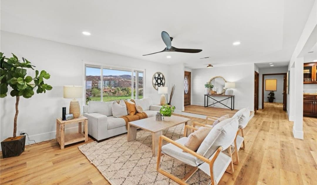 Modern living room with cozy furnishings, large windows, and natural light, featuring wood accents.