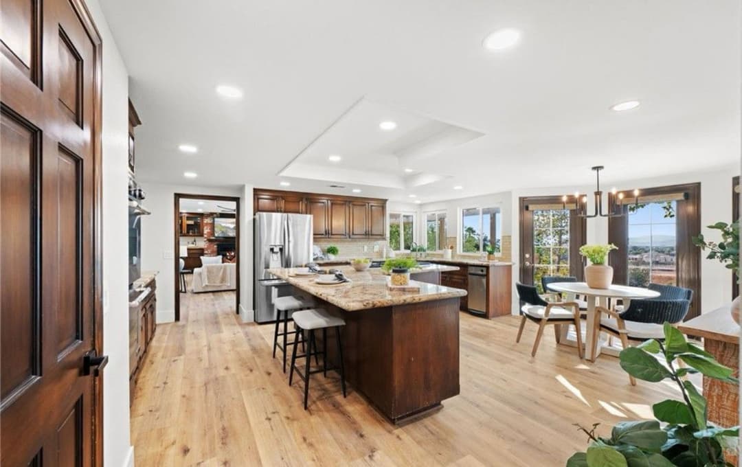 Modern kitchen with granite island, wood cabinets, and natural light from large windows.