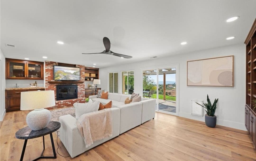Modern living room featuring a cozy white sofa, wooden flooring, and large windows with a scenic view.