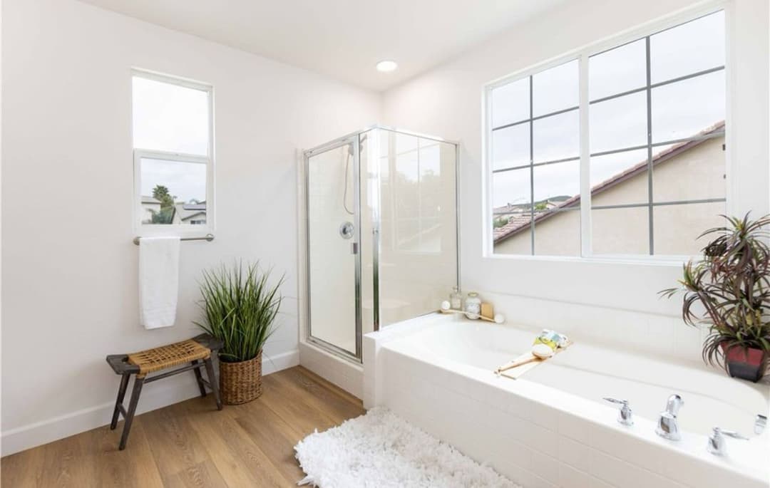Modern bathroom with shower, bathtub, large windows, and stylish decor. Bright, spacious design.