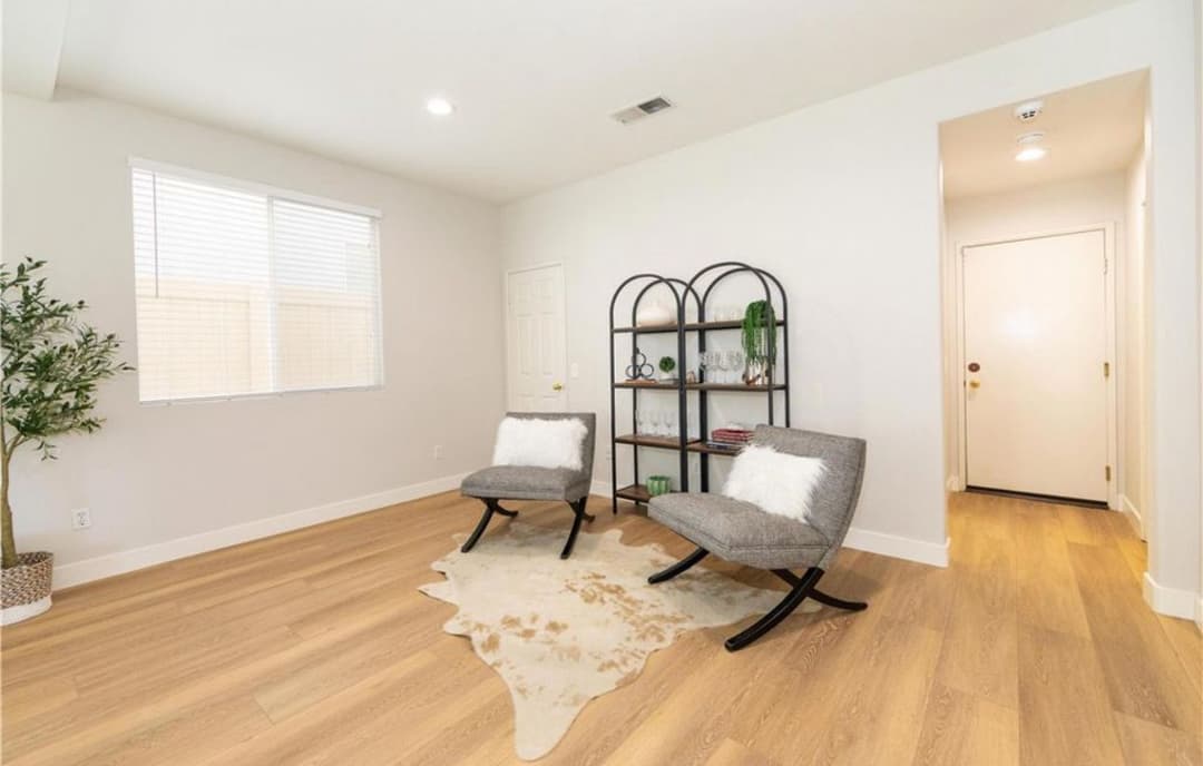 Stylish modern living room with gray chairs, brown carpet, and natural light.