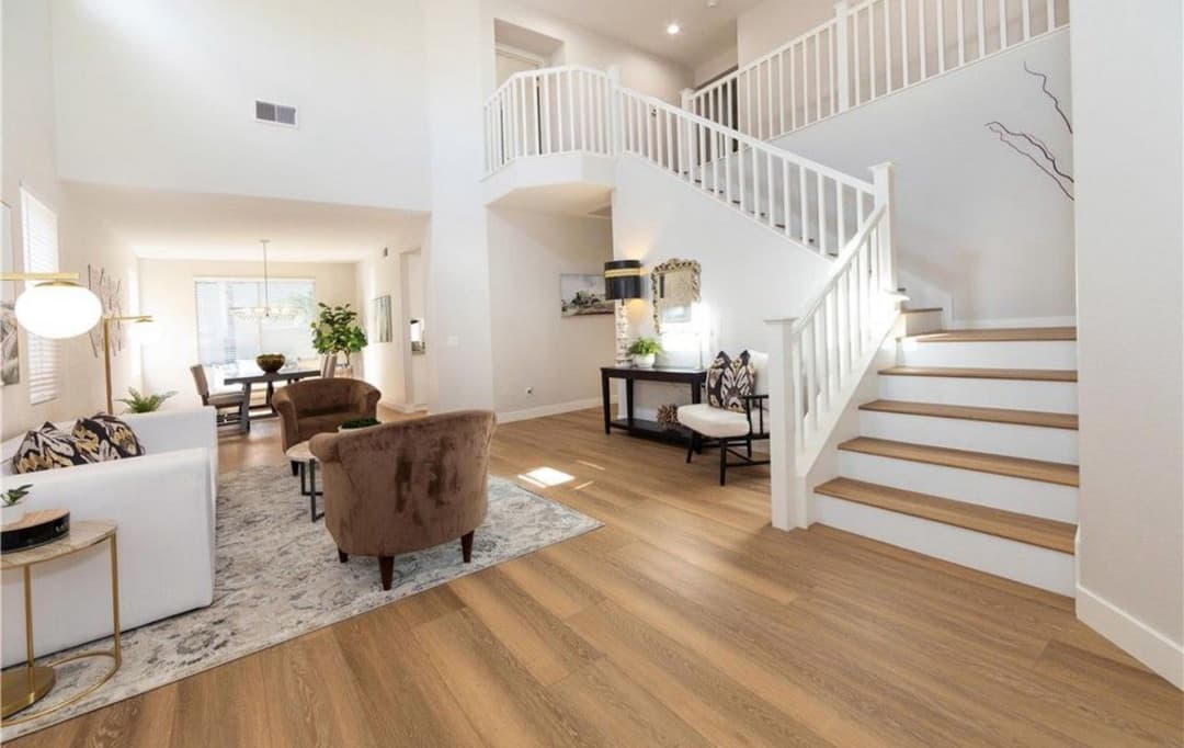 Modern open-concept living room featuring a staircase, natural light, and stylish decor.
