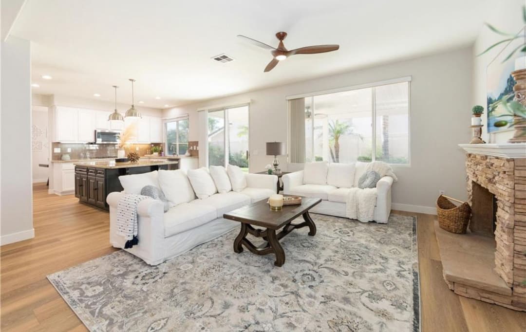 Bright and airy living room with white sofa, wooden coffee table, and stone fireplace accents.