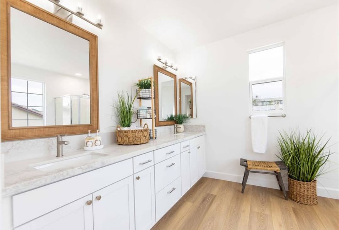 Modern bathroom with dual mirrors, wooden accents, and houseplants for a fresh ambiance.