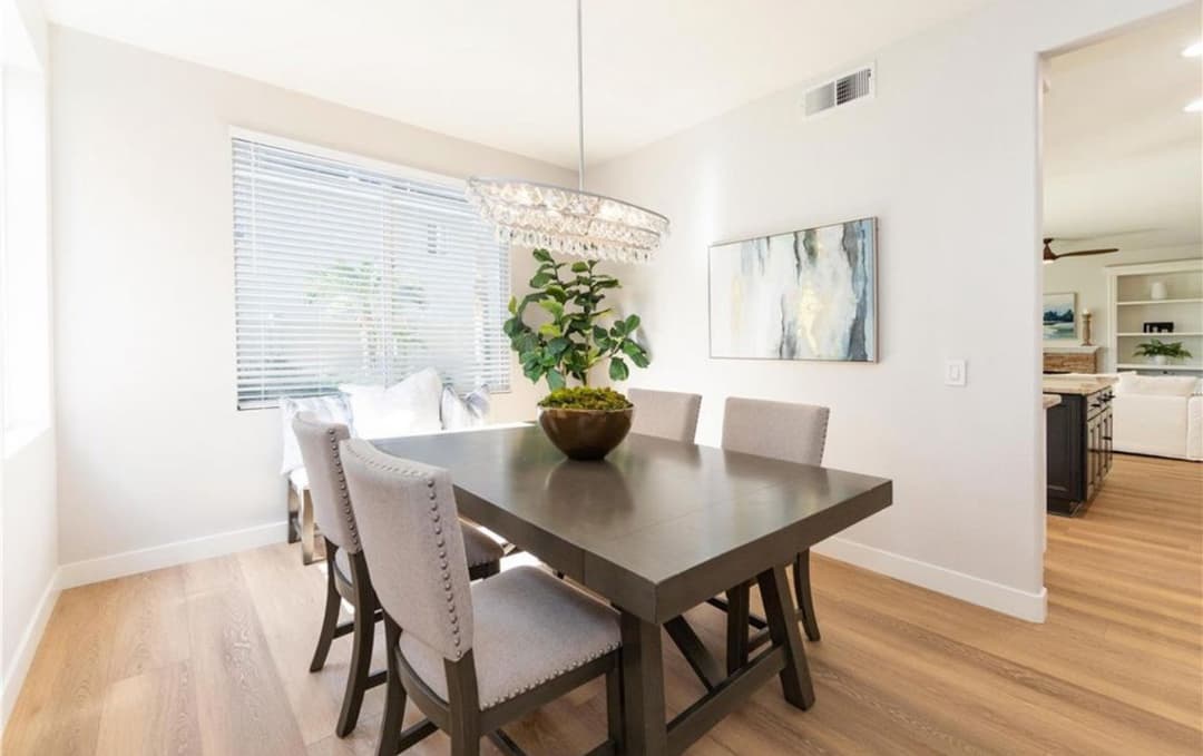 Modern dining room with a stylish table, elegant chandelier, and indoor plant decor.