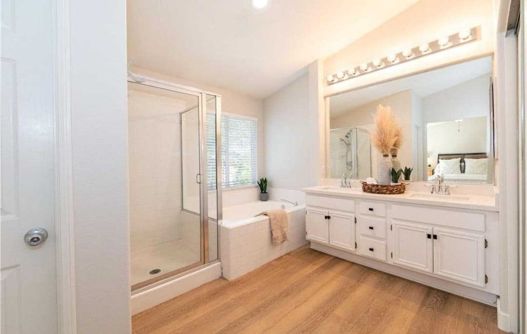 Modern bathroom with double sinks, walk-in shower, and stylish decor, featuring natural light.