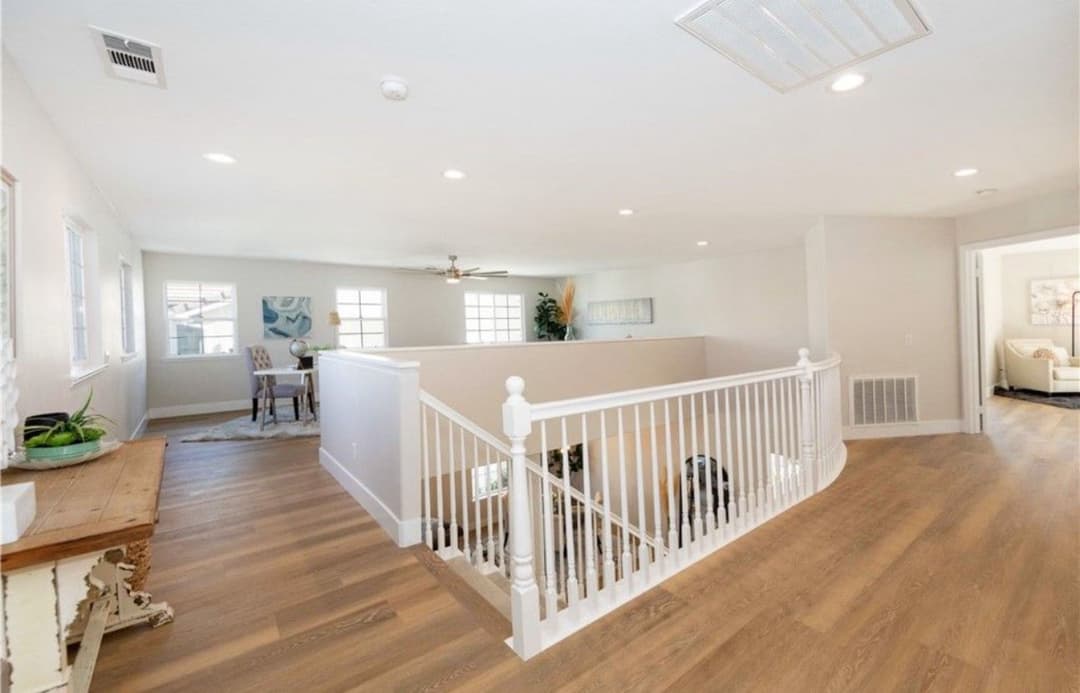 Spacious interior view of a bright two-story home with modern staircase and wood flooring.