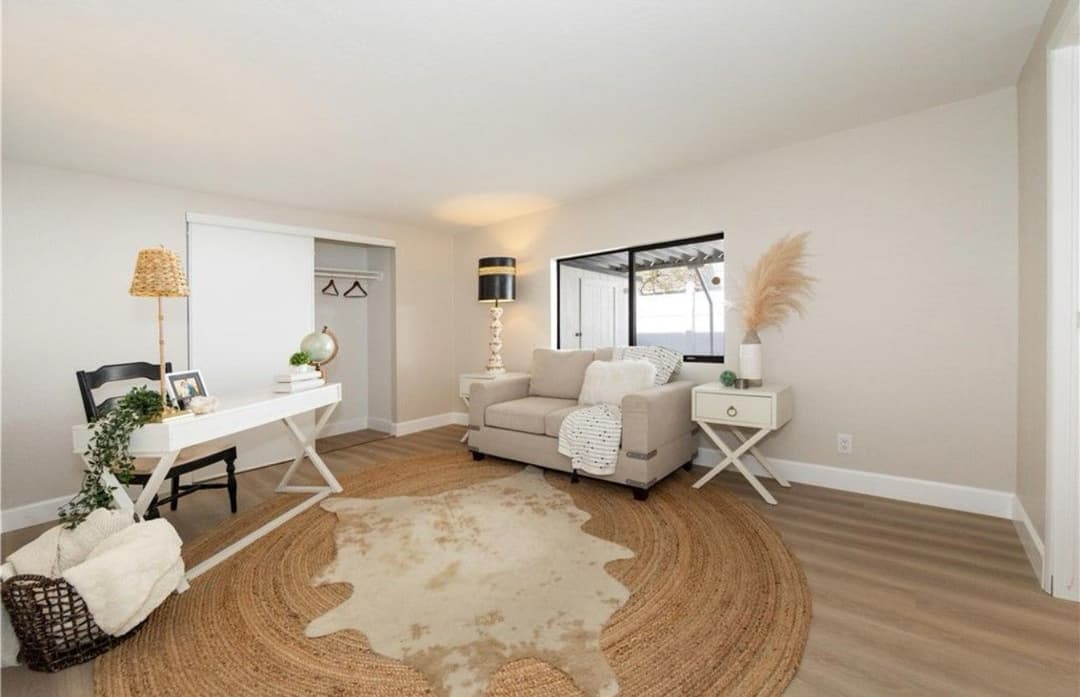 Modern living room with beige decor, a cozy sofa, a decorative rug, and a stylish workspace.