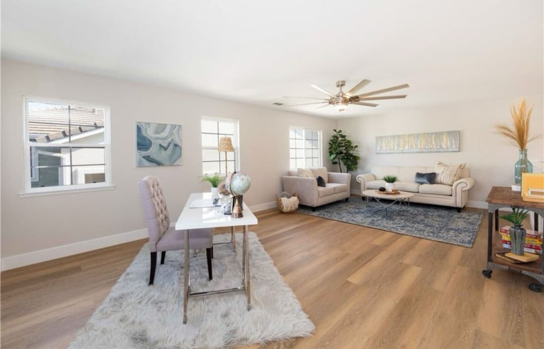 Bright, modern living room with a cozy sofa, desk, and stylish decor on wooden flooring.
