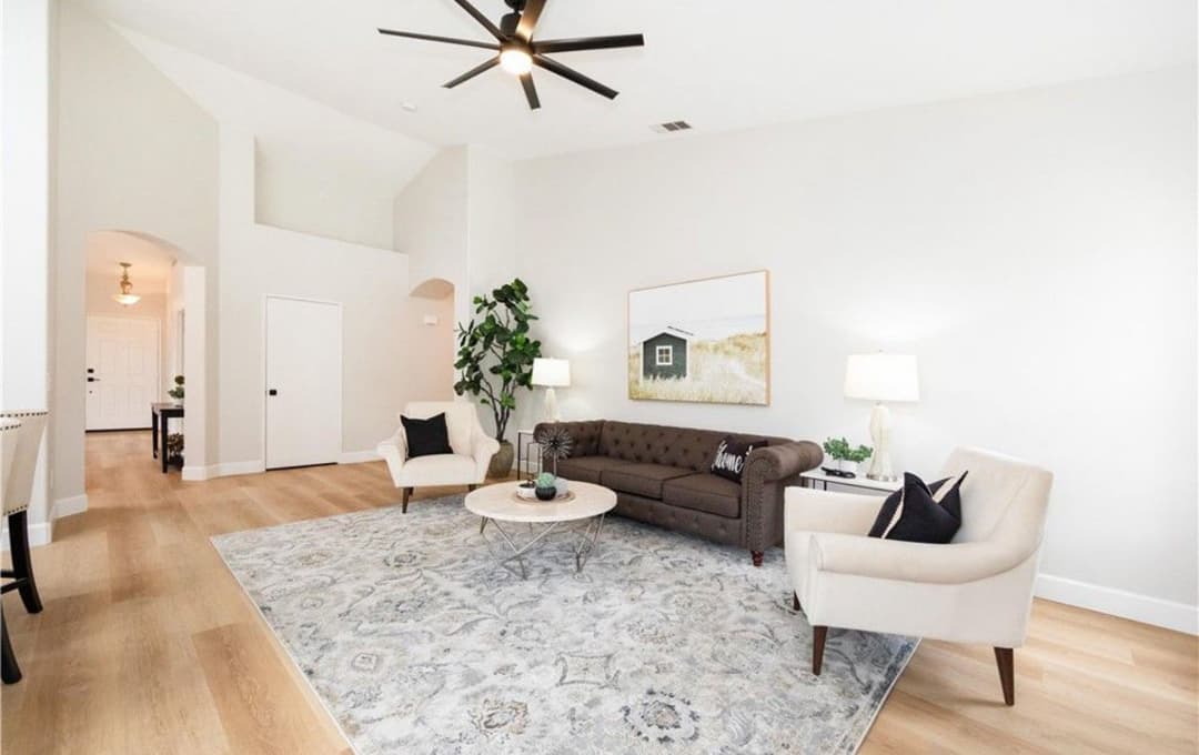 Modern living room with stylish furniture, area rug, and large ceiling fan, bright and spacious.