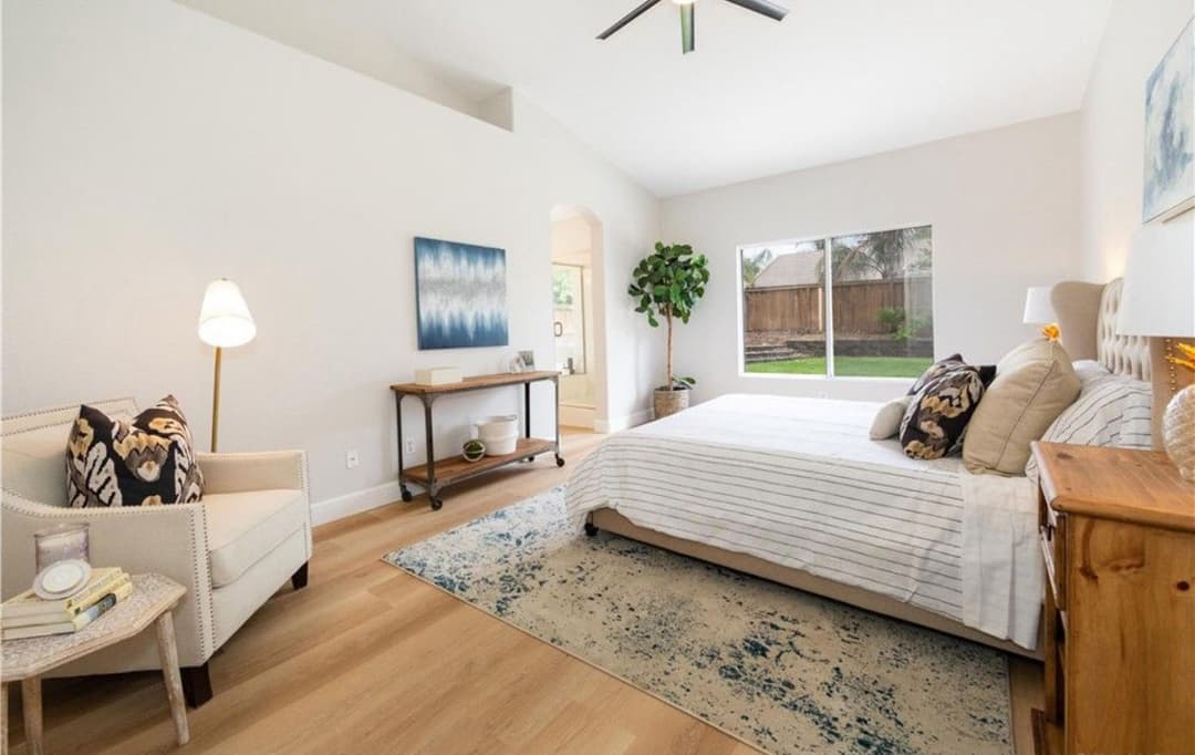 Bright, modern bedroom with sitting area, large window, and stylish decor.