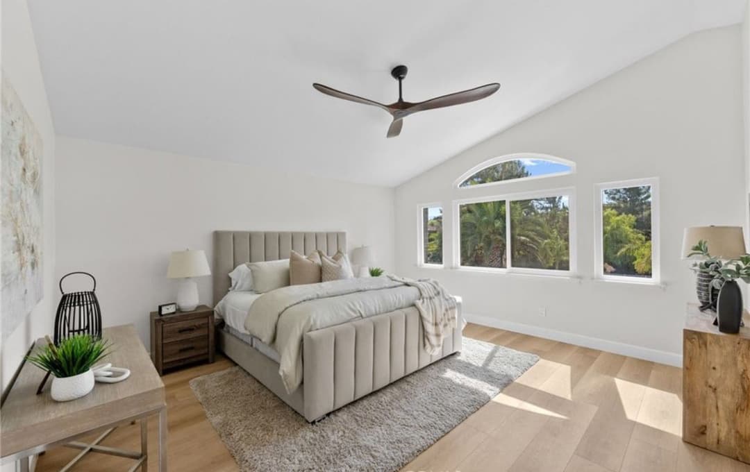 Stylish modern bedroom with large windows, neutral tones, and sleek ceiling fan.