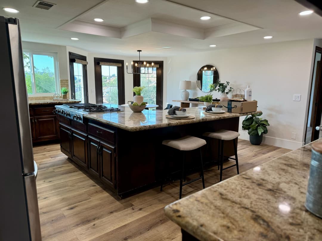 Modern kitchen with island, granite countertops, stainless steel appliances, and natural light.