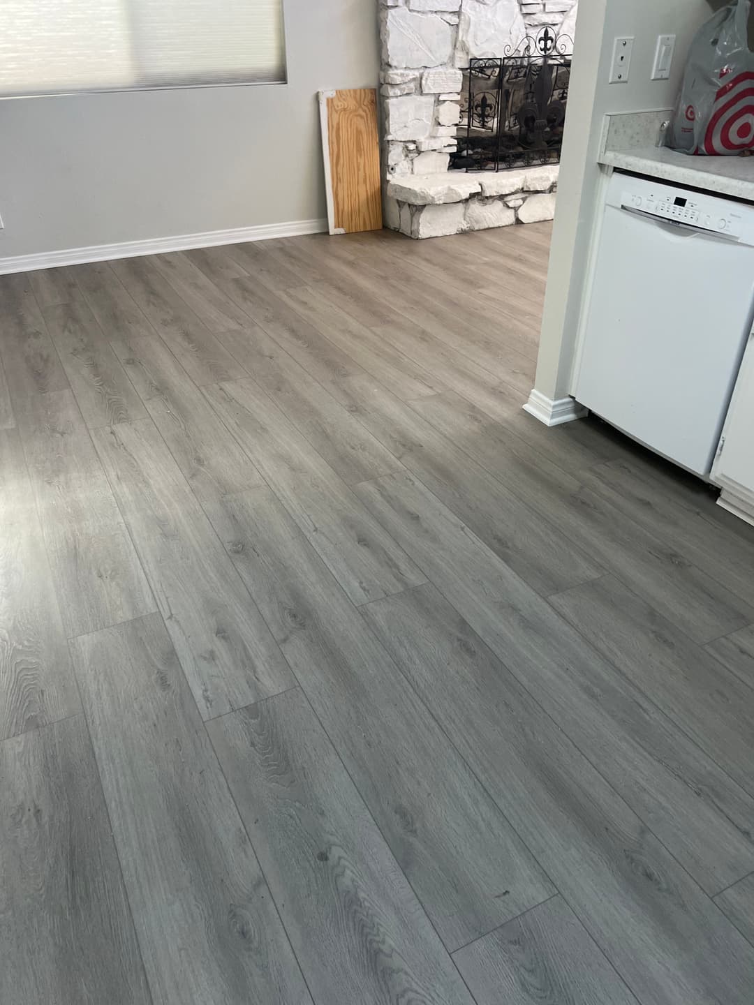 Modern living room with light gray laminate flooring and a stone fireplace.