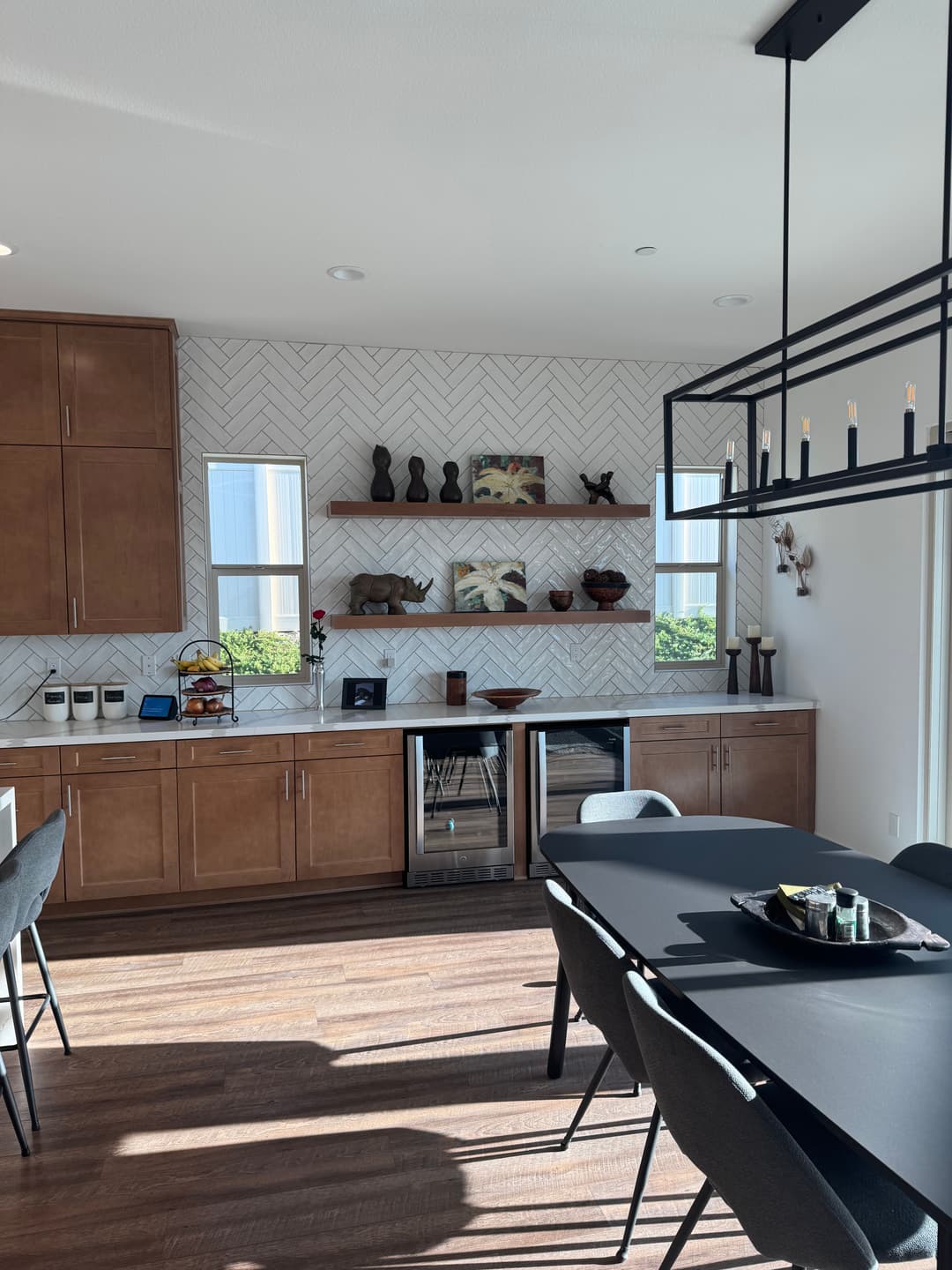 Modern kitchen with herringbone backsplash, wooden cabinets, and a sleek dining table.