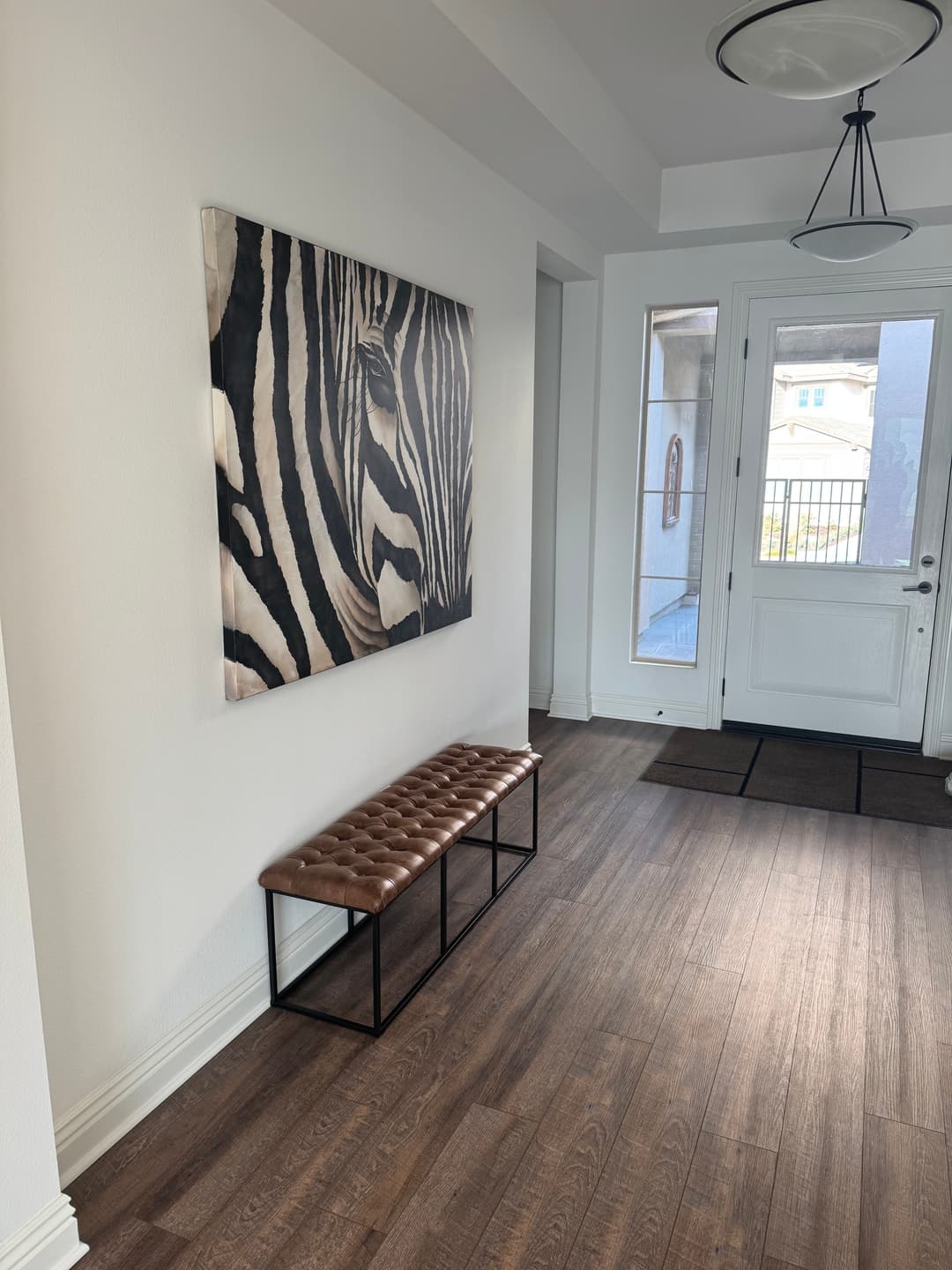 Zebra art hanging in a modern hallway with a stylish bench and front door entry.