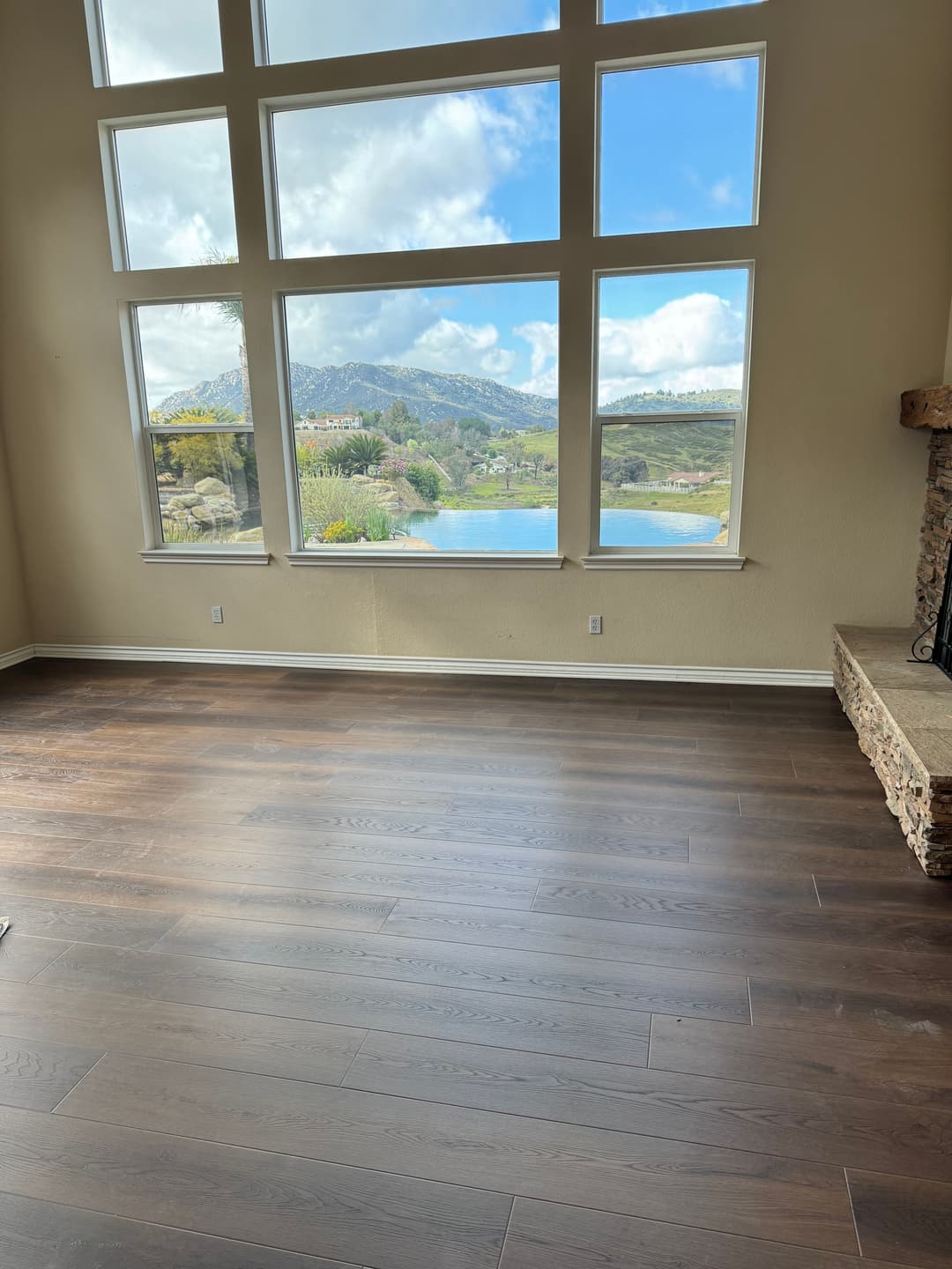 Spacious living room with large windows showcasing a scenic mountain view and hardwood floors.
