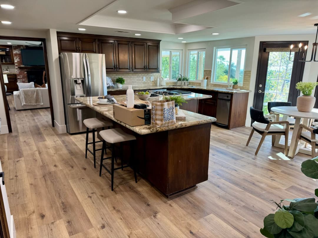 Modern kitchen with granite island, wooden cabinets, and open layout showcasing natural light.