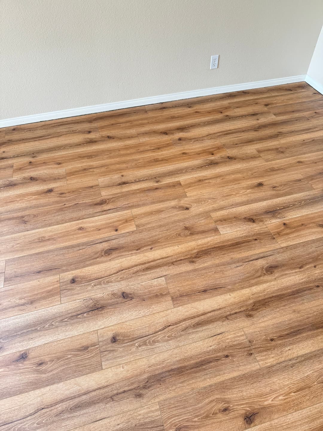 Newly installed wood laminate flooring in a bright, empty room.