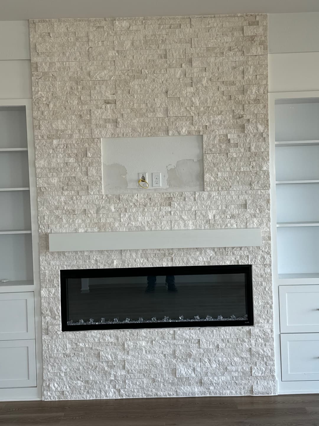 Modern living room featuring a stone fireplace with a minimalist design and built-in shelves.