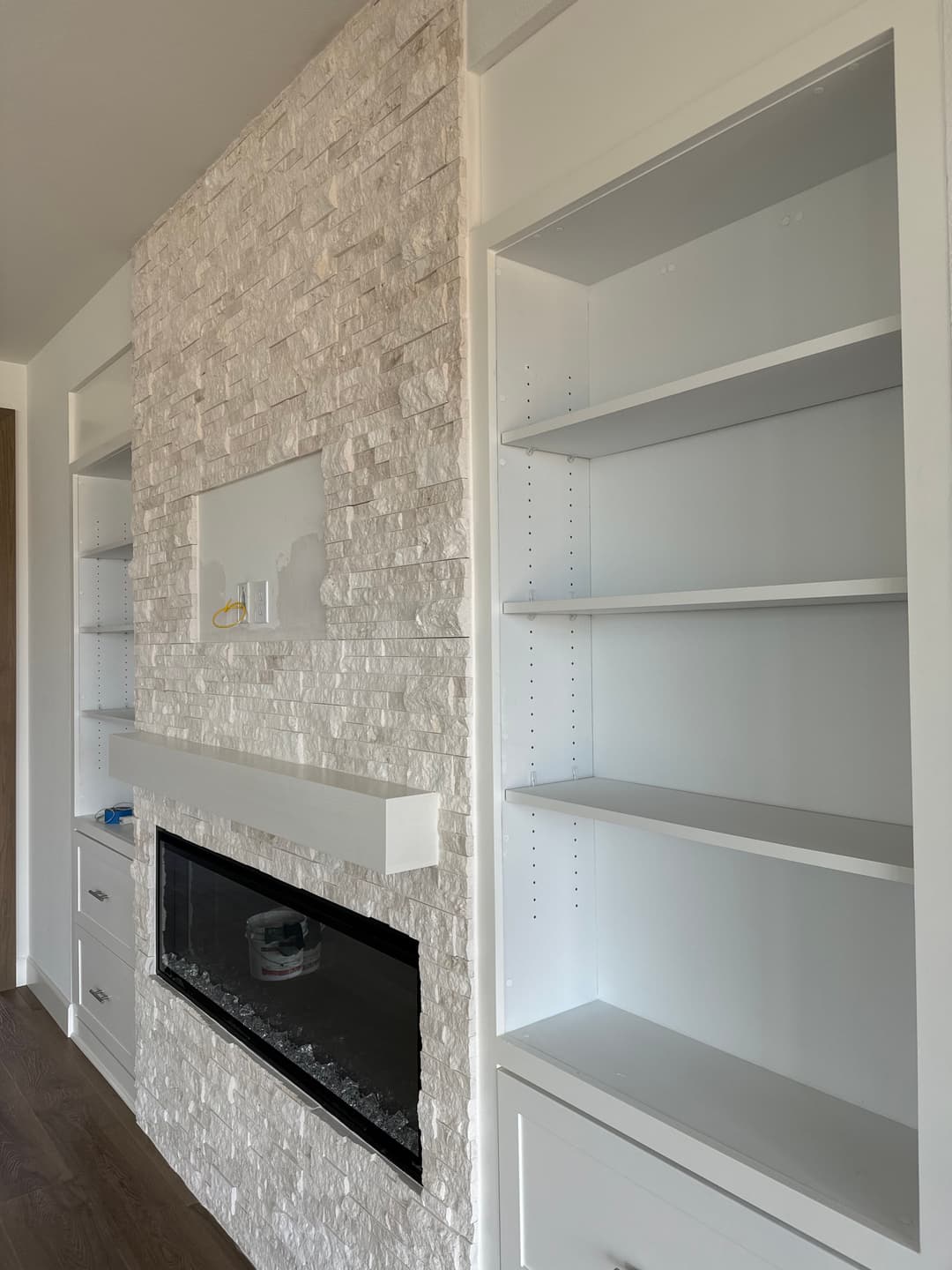 Modern living room with white stone fireplace and built-in shelves. Elegant, minimal design.