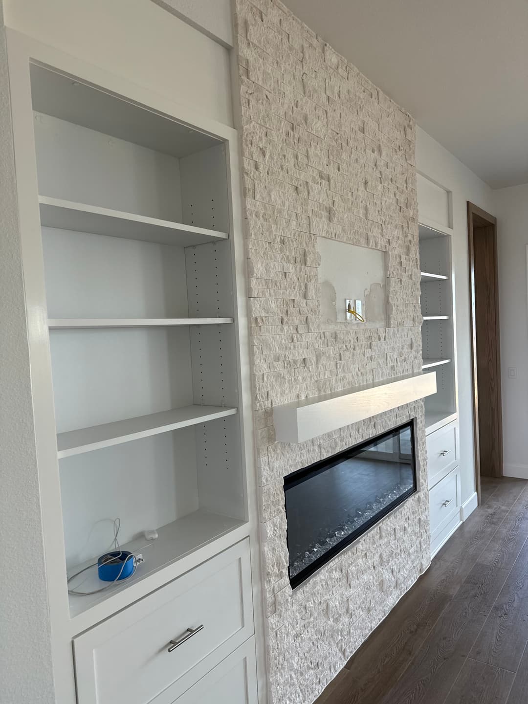 Modern living room with stone accent wall and sleek built-in shelves around a linear fireplace.