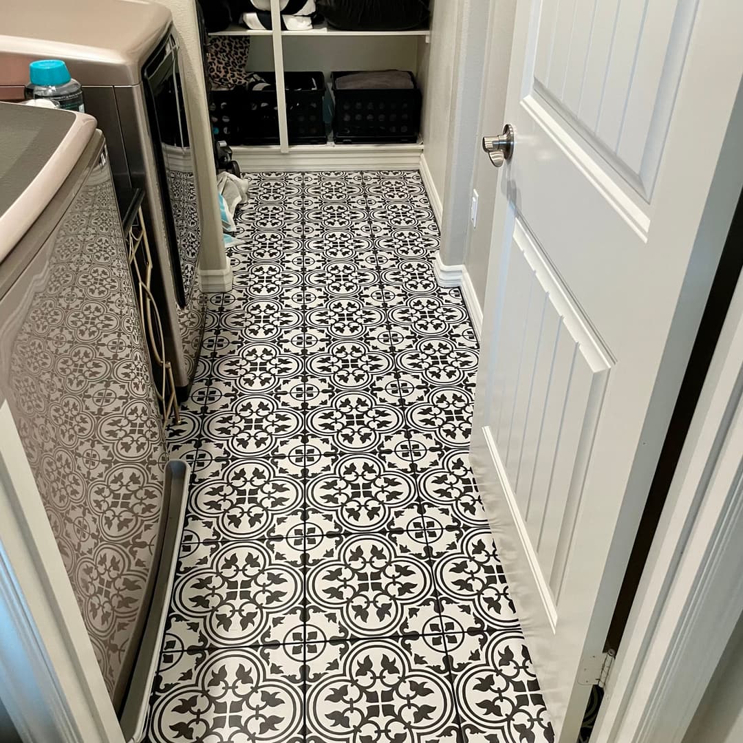Modern laundry room with stylish black and white patterned tile flooring and organized storage.
