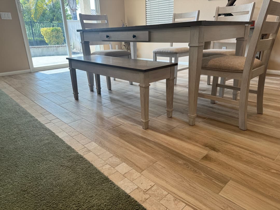Dining area with wooden furniture, tile flooring, and a view of outdoor greenery.