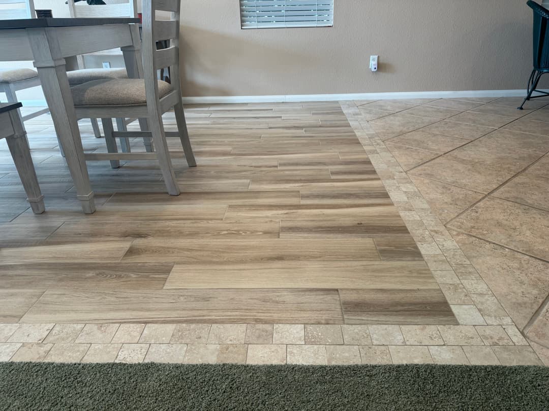 Modern wood and tile flooring transition in a living space with a dining table.