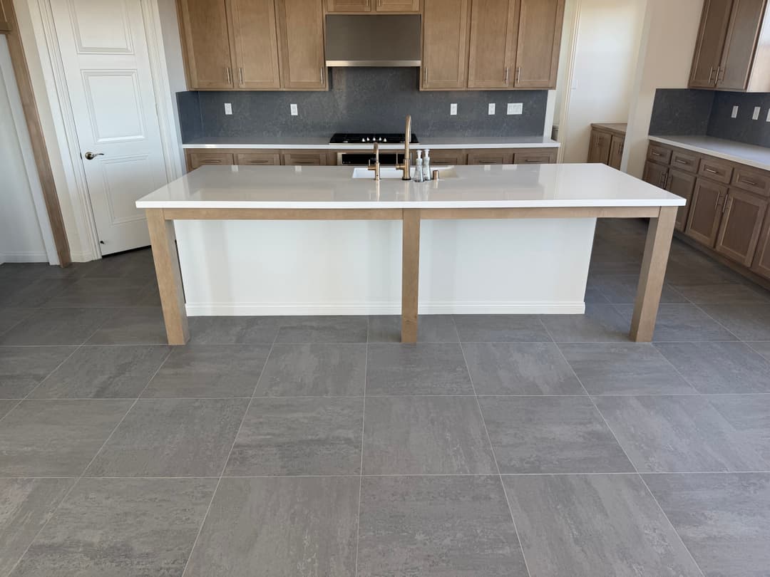 Modern kitchen with a central island, sleek countertops, and gray tiled flooring.