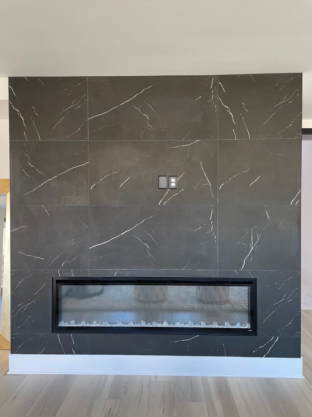Modern wall-mounted fireplace with sleek dark tiles and minimalist design elements.