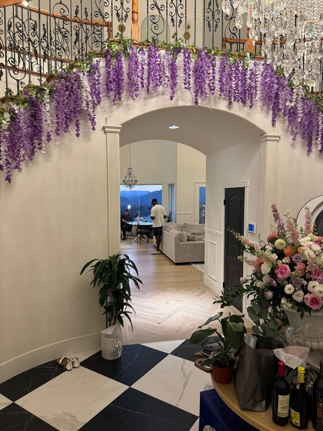 Indoor entryway with floral decor, leading to a cozy living area with large windows.