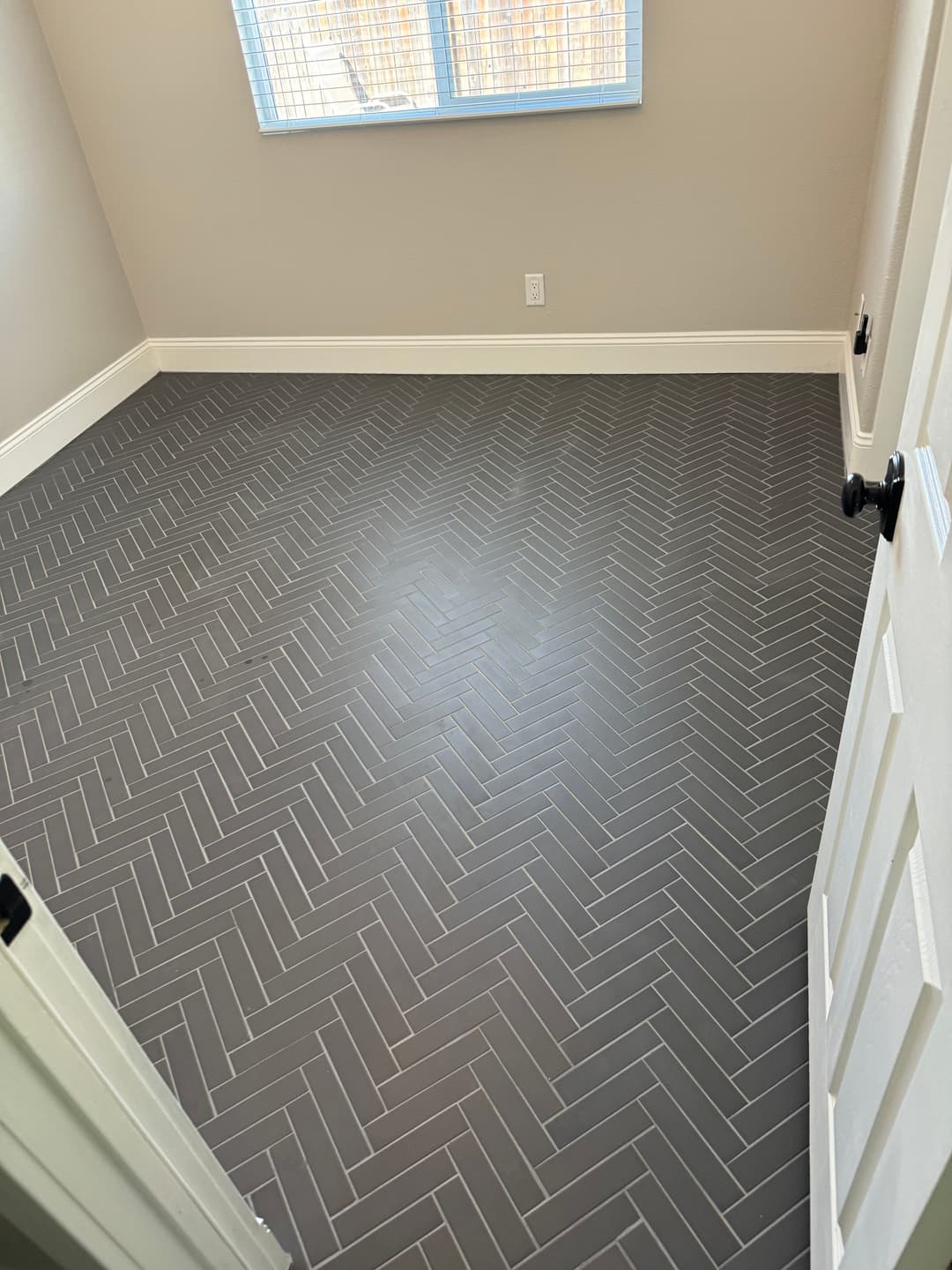 Herringbone patterned gray tile flooring in a well-lit room with natural light.