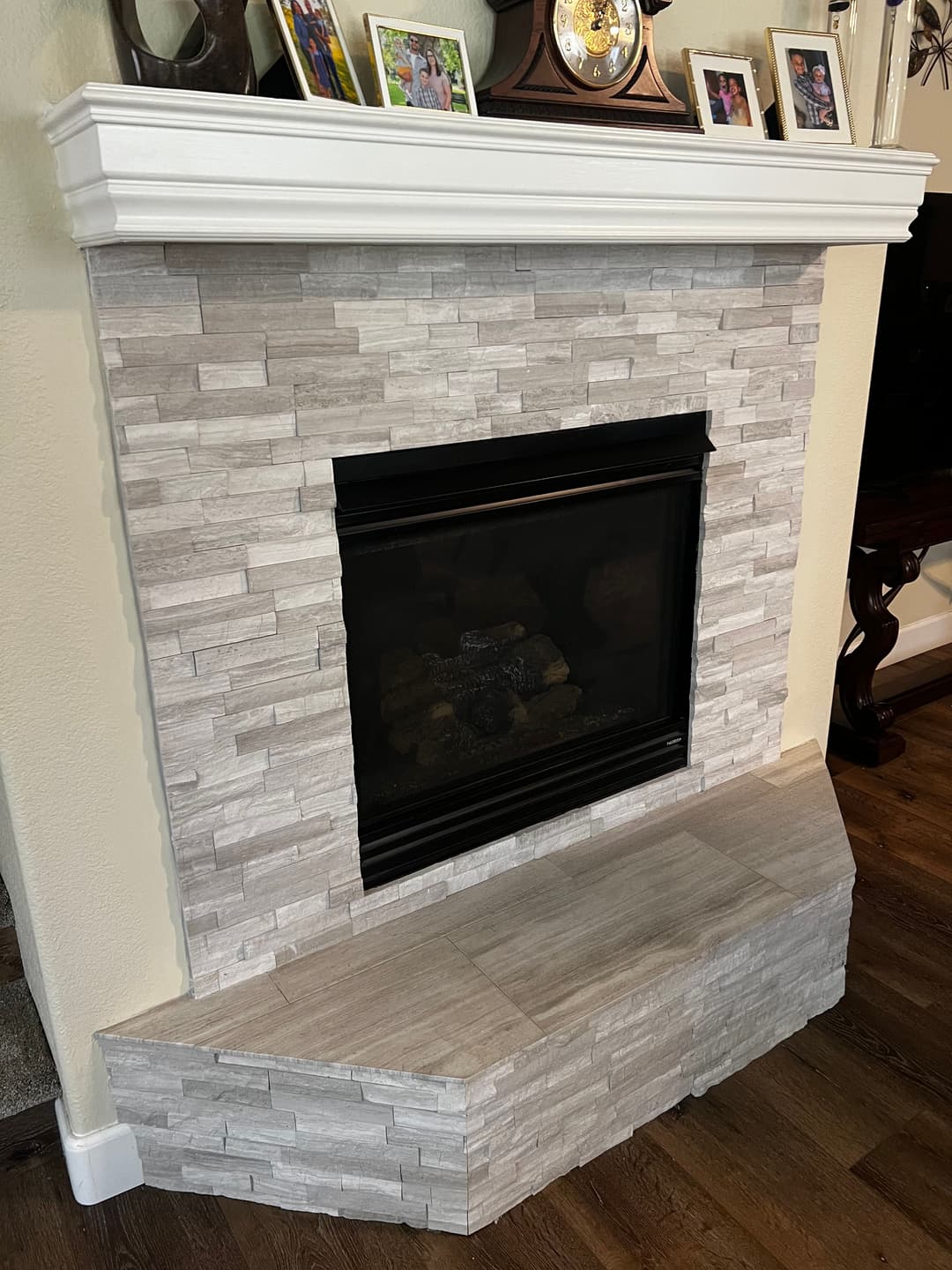 Modern fireplace with textured stone surround and wooden mantel, featured in a cozy living room.