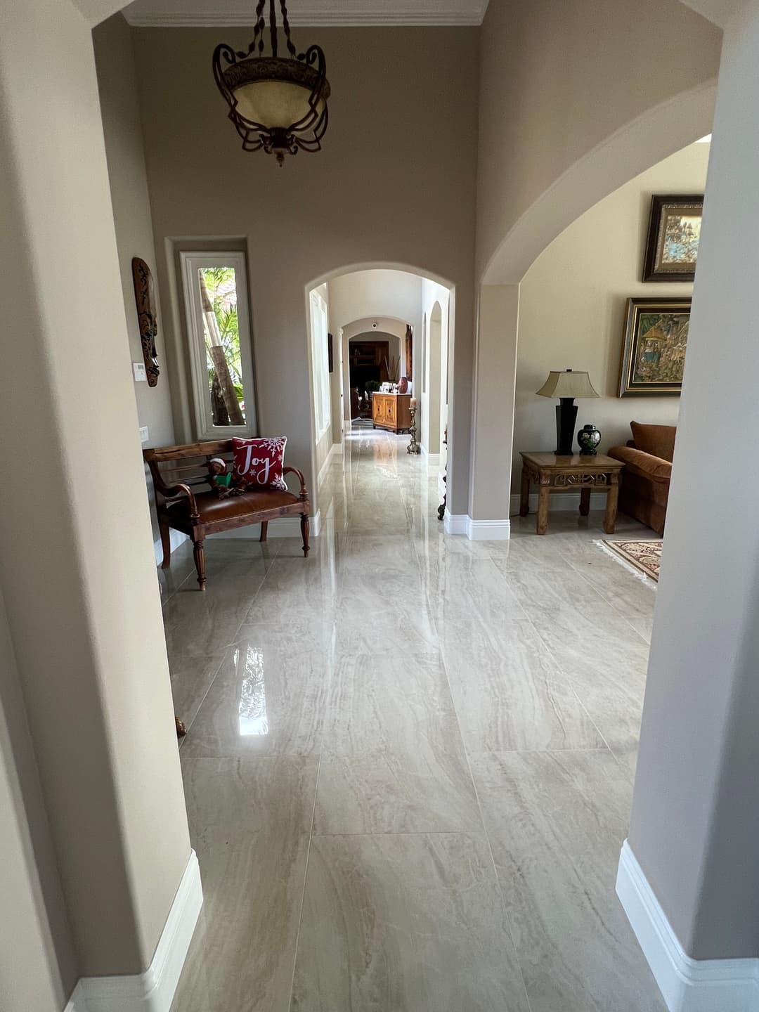 Spacious hallway with glossy tile flooring, decorative arches, and cozy seating area.