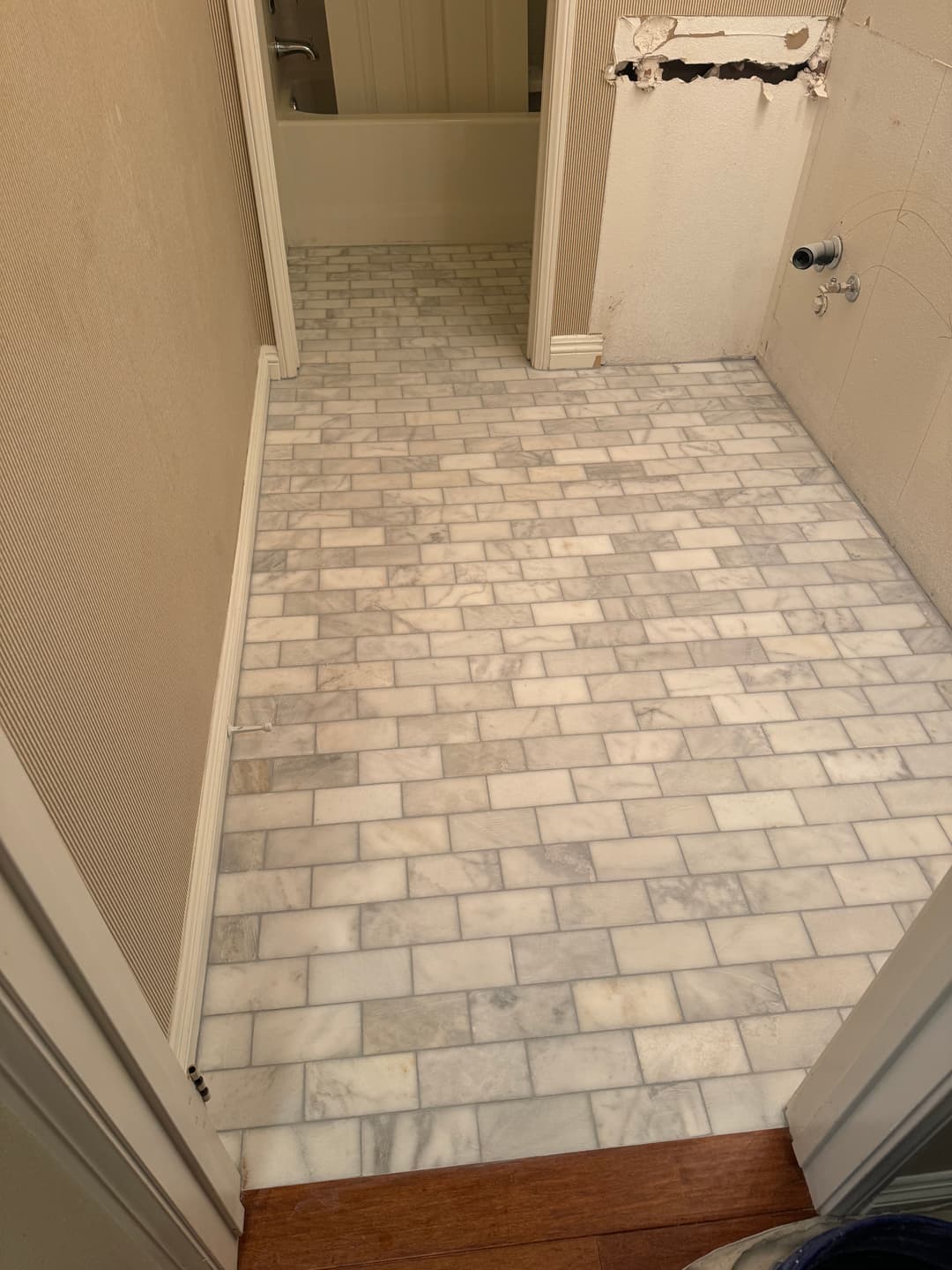 Marble tile flooring in a bathroom under renovation with visible plumbing fixtures.