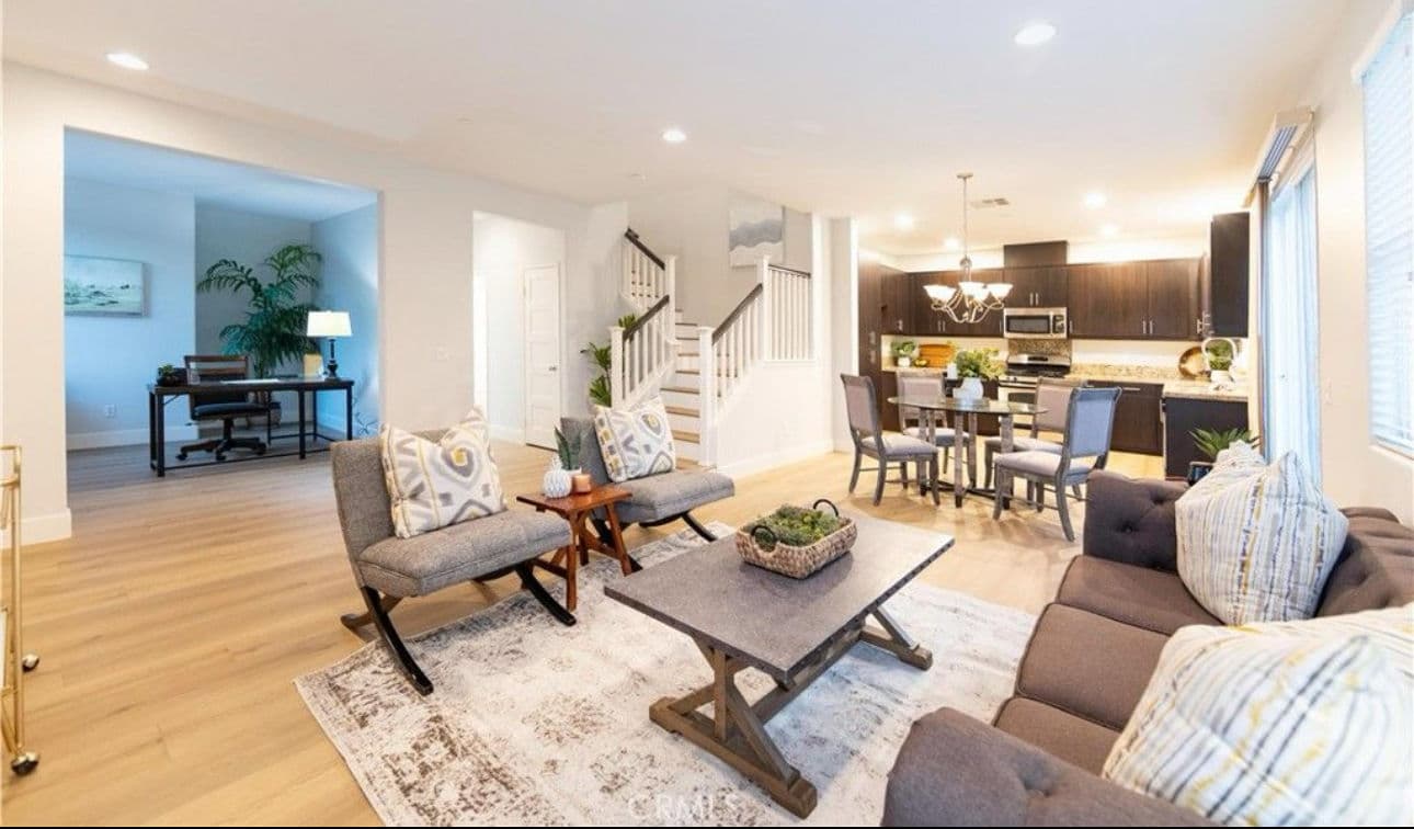 Modern open-concept living room with stylish furniture, dining area, and kitchen. Natural light.