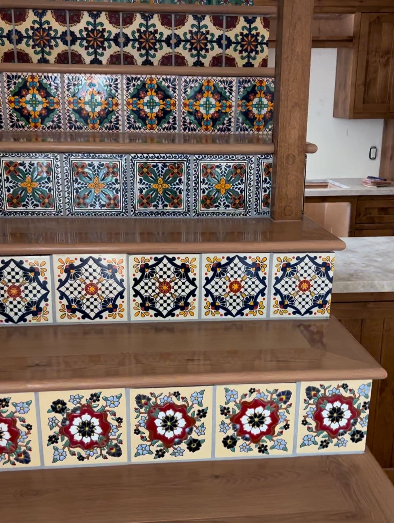 Colorful tile backsplash on wooden stairs, showcasing intricate patterns and designs.