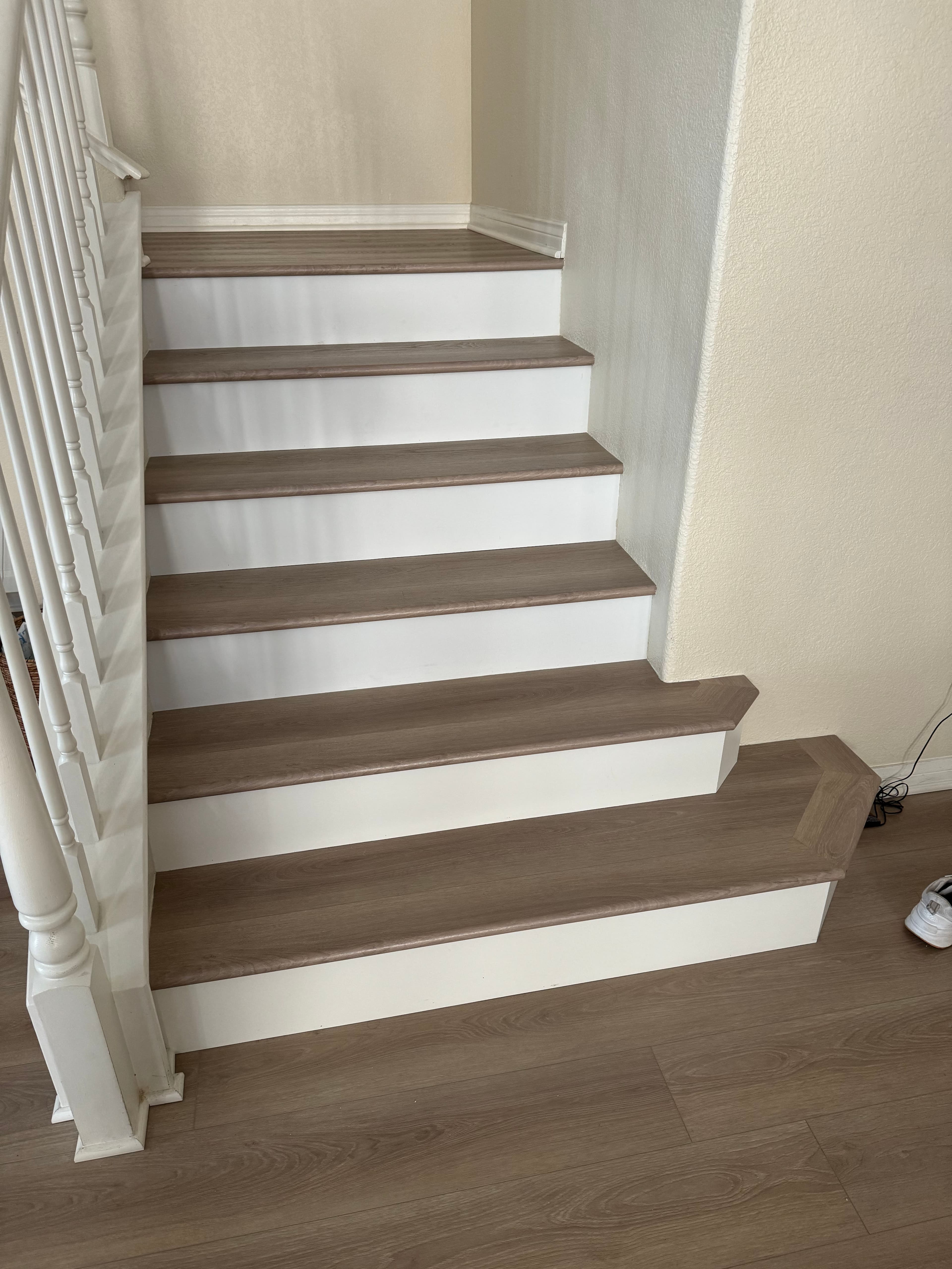 Modern staircase with white risers and beige wooden treads in a well-lit interior.