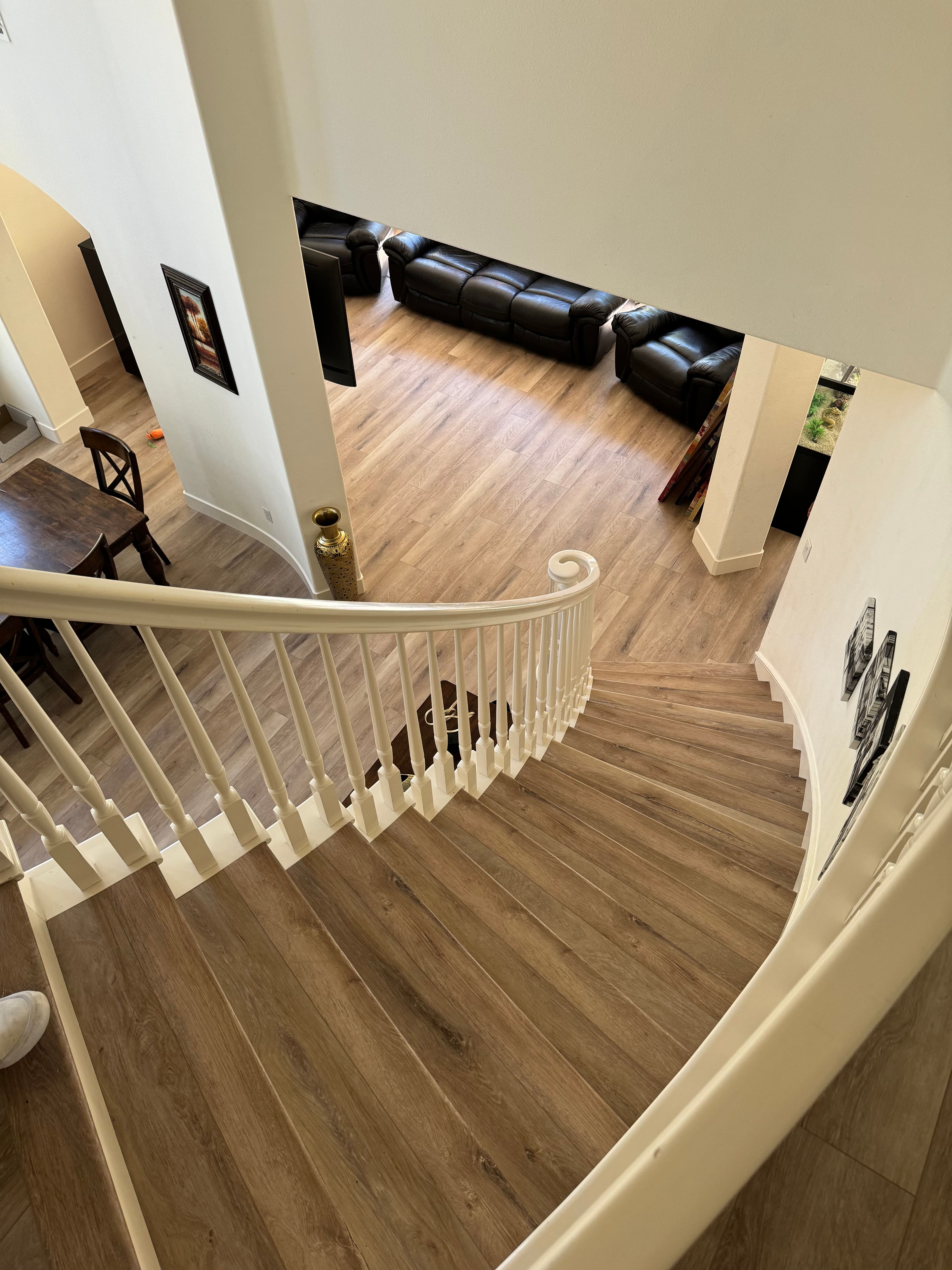View of a spiral staircase leading to a spacious living room with dark leather furniture.