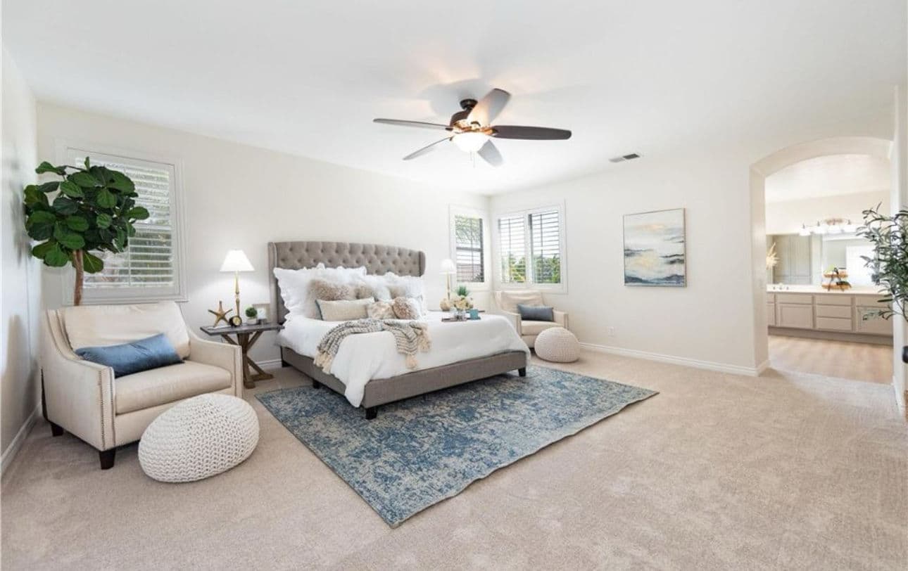 Spacious, modern bedroom with king bed, cozy seating, and natural light accents.