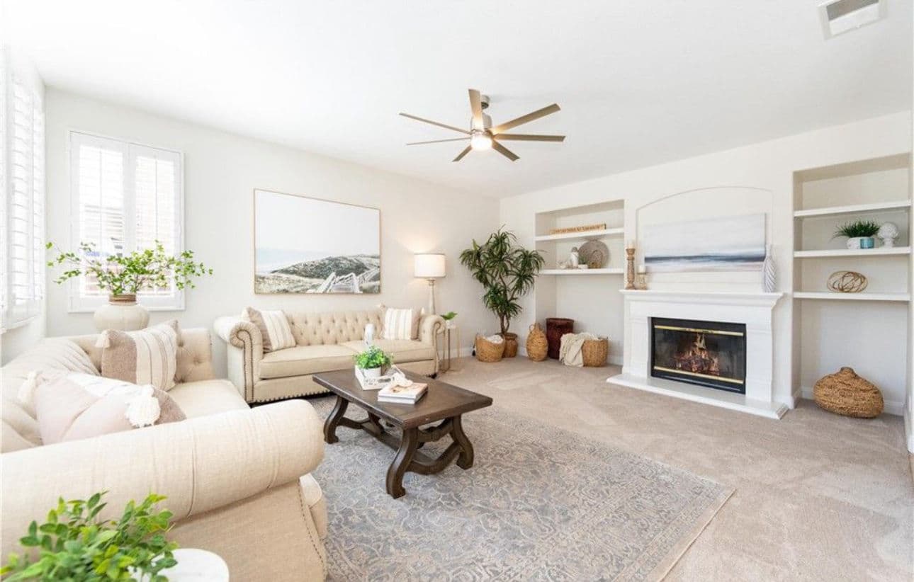 Stylish living room with beige sofa, decorative plants, and modern fireplace decor.