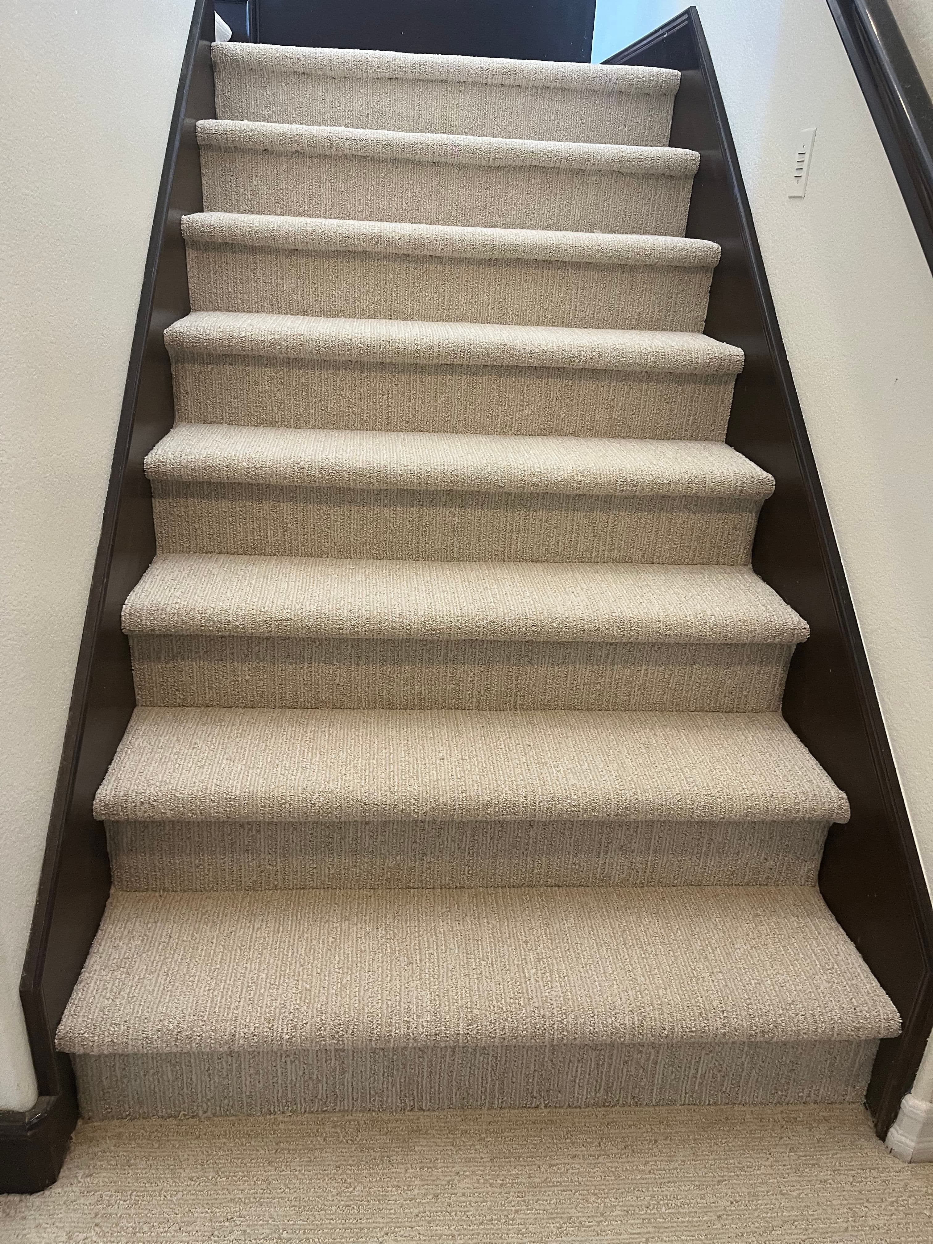 Carpeted staircase with light gray steps leading to a top landing. Modern home interior design.