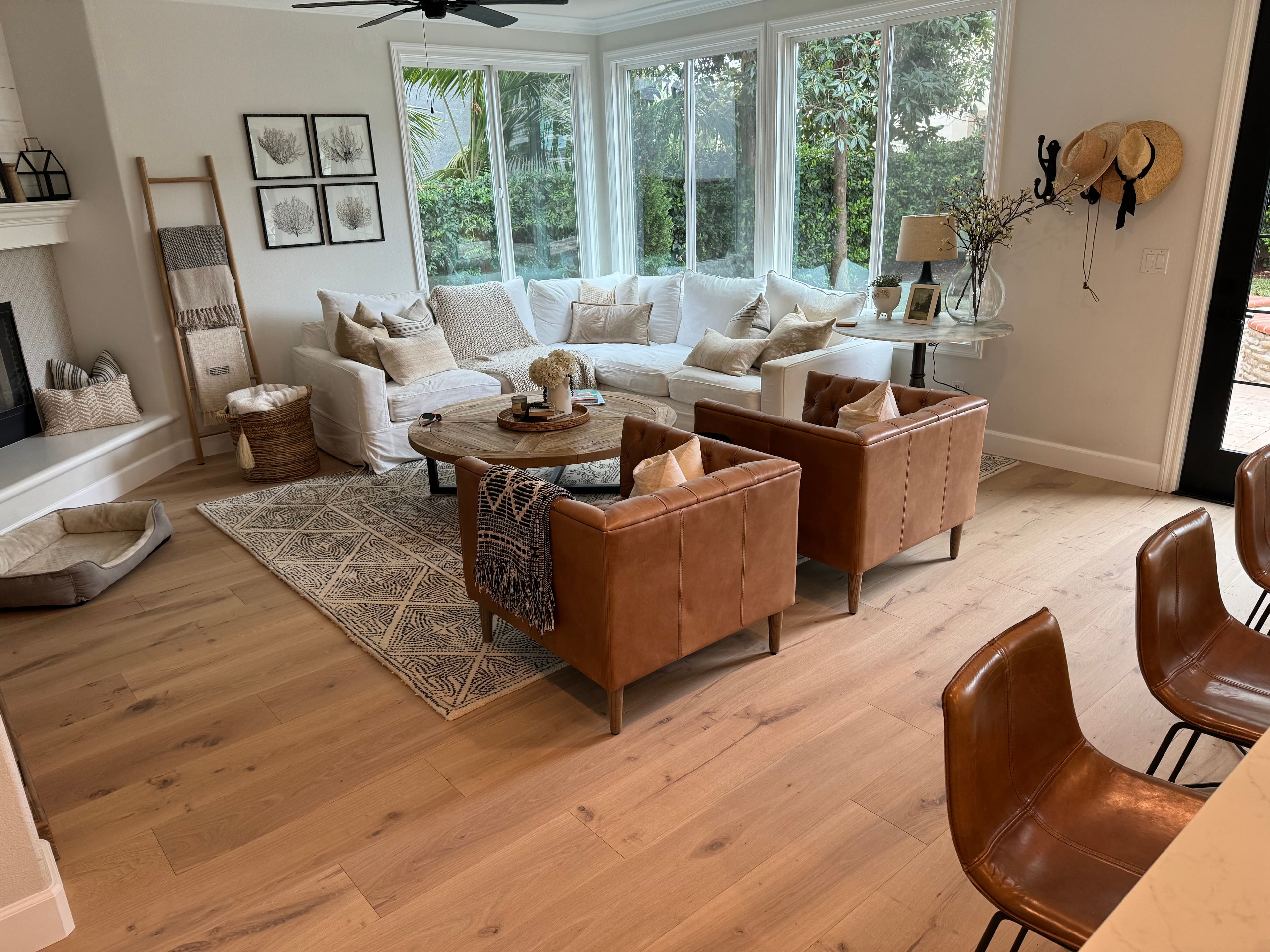 Cozy living room featuring a white sofa, brown leather chairs, and large windows with natural light.